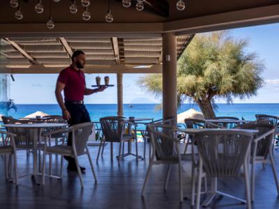 Cameriere serve bevande in un ristorante con vista mare.