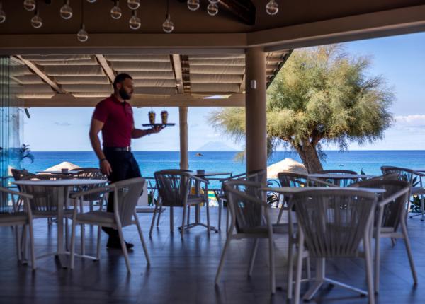 Cameriere serve bevande in un ristorante con vista mare.