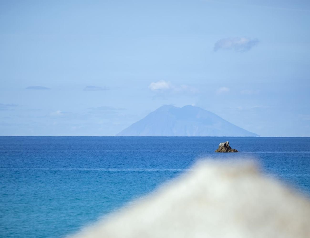 Île volcanique vue depuis la mer avec ciel clair.