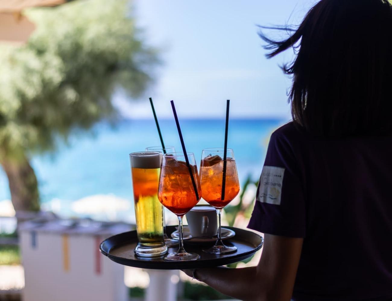 Waiter serves cocktails with sea view.