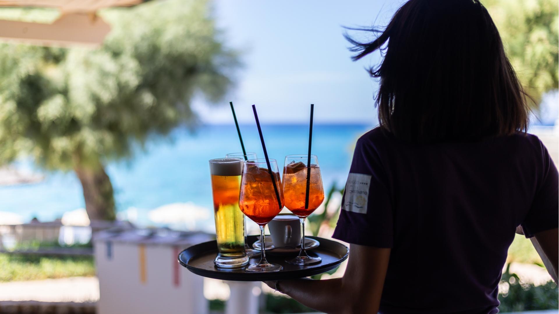 Cameriere serve drink con vista mare.