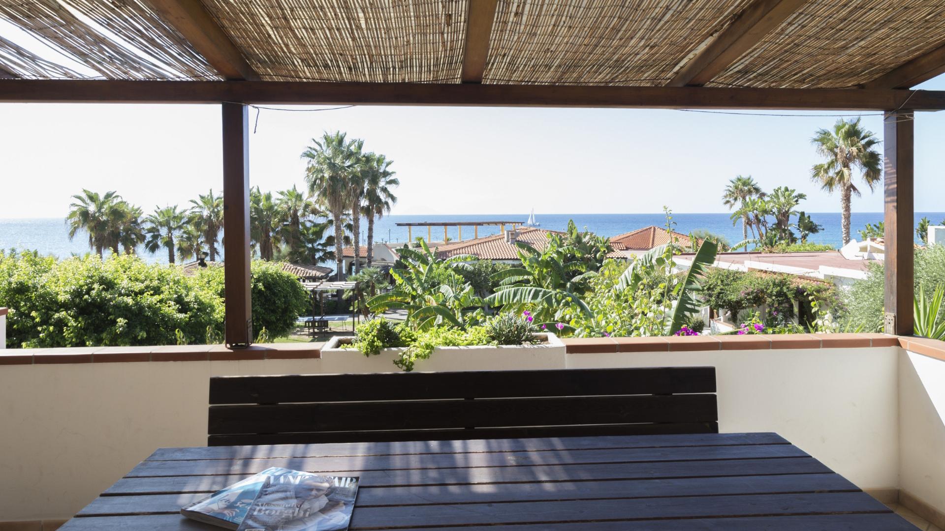 Terrazza con vista mare e palme, atmosfera rilassante.