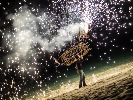 Persona con struttura pirotecnica sulla spiaggia di notte.