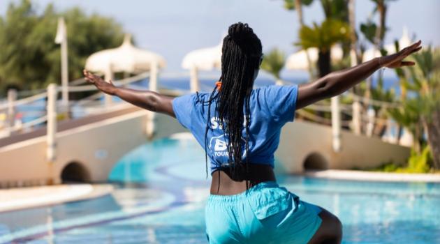 Person doing yoga by a pool.