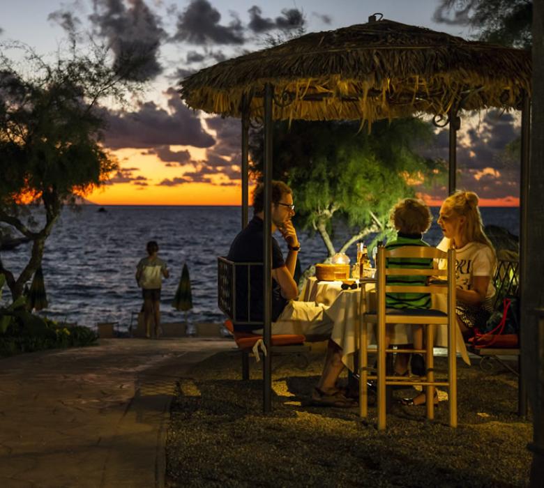 Famiglia cena al tramonto sul mare, atmosfera rilassante.