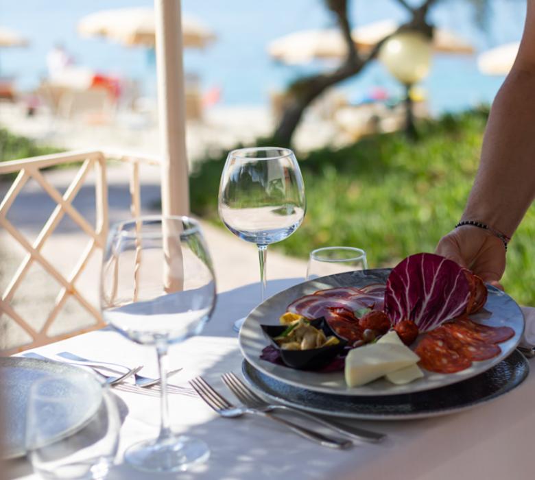 Piatto di salumi servito al tavolo con vista mare.