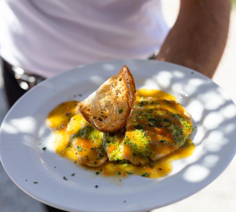 Piatto di ravioli con salsa e crostino.