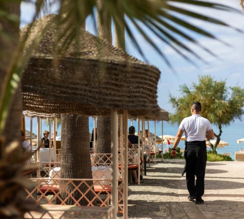 Cameriere cammina verso il mare in un ristorante all'aperto.