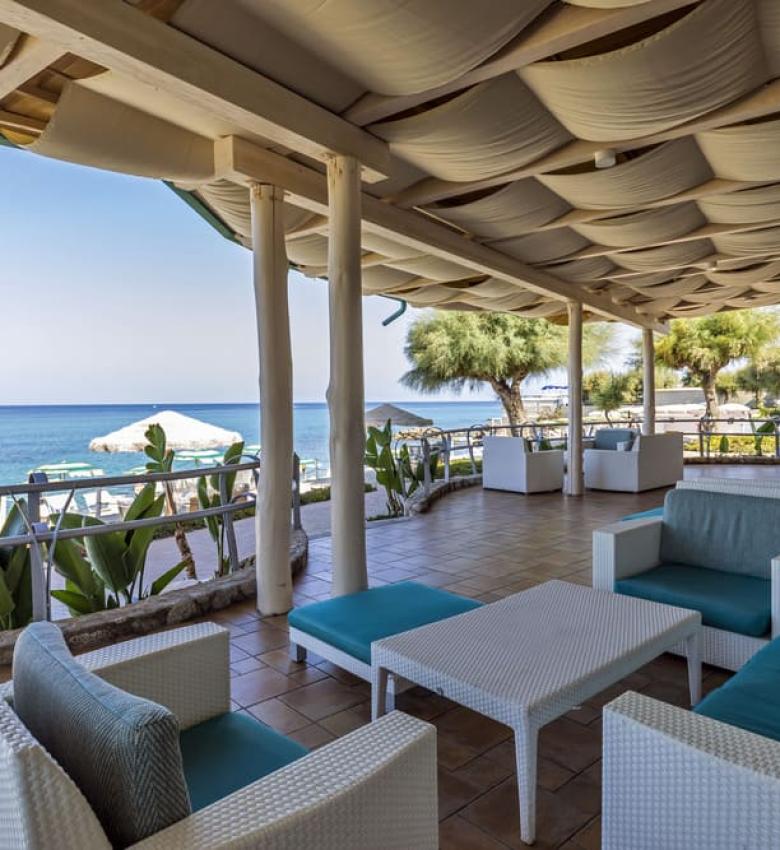 Terrazza sul mare con sedie bianche e vista panoramica.