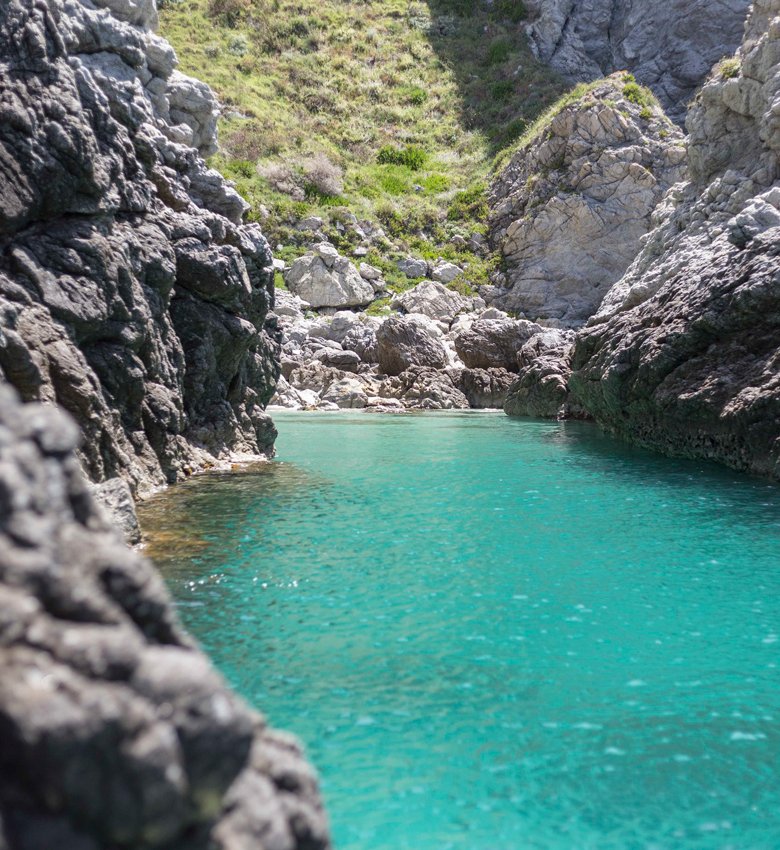 Acqua cristallina e scogliere rocciose in una baia tranquilla.