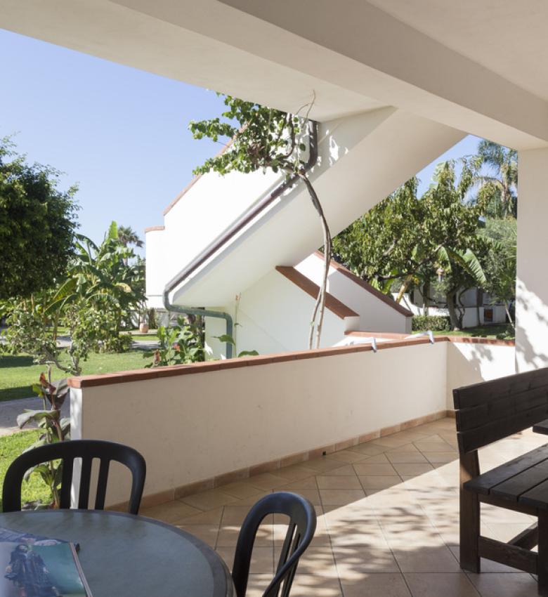 Terrazza soleggiata con tavolo e vista sul giardino verde.