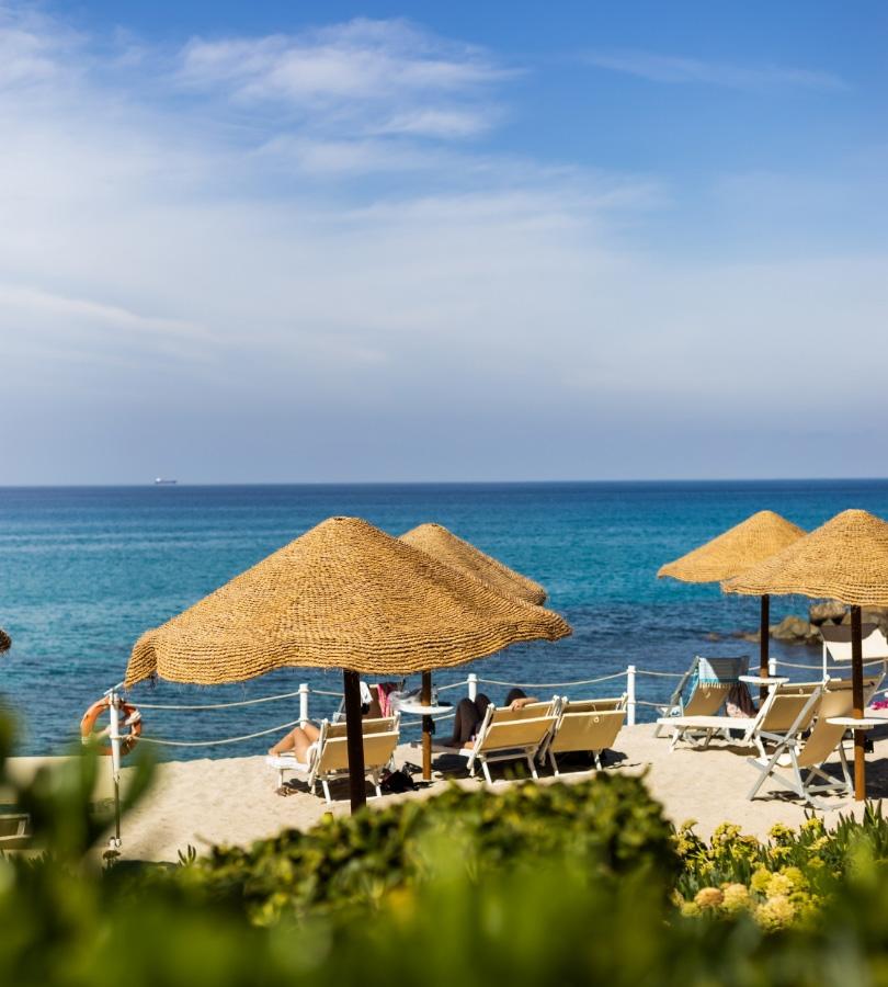 Sunny beach with umbrellas and loungers, clear sea.